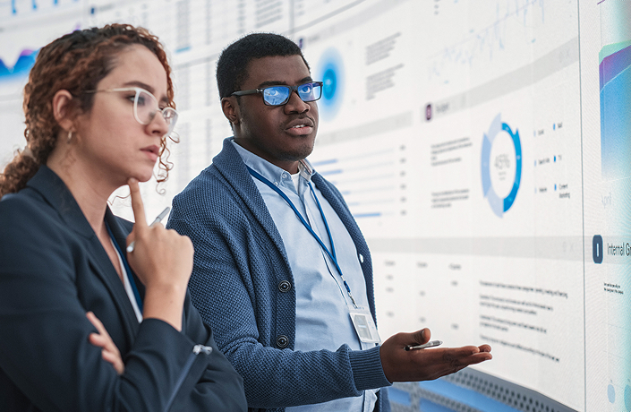 Two professionals analyzing data on a dashboard, representing background screening insights and compliance decision-making.