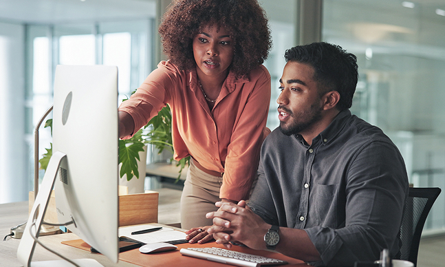 Two professionals reviewing hiring data on a desktop computer, representing employment screening analysis and decision-making.