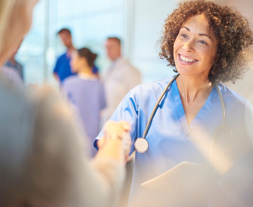 Healthcare professional greeting a patient, representing hospital workforce and compliant employment screening.
