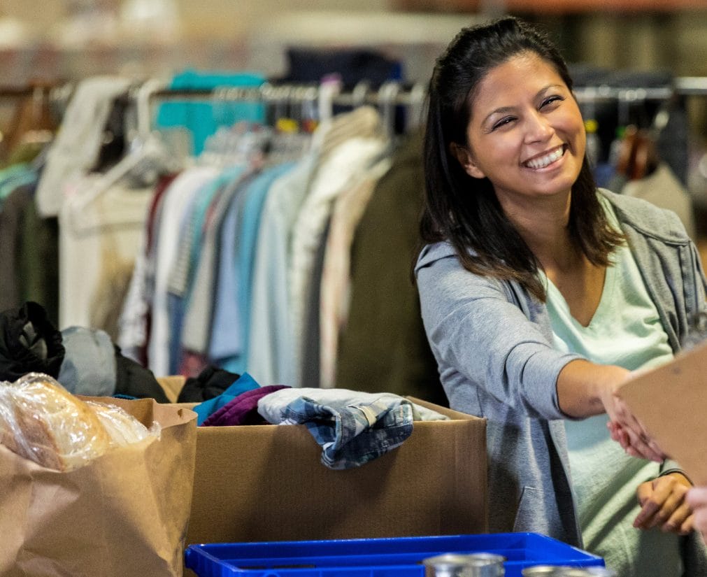 Volunteer handing donations to a community member at a nonprofit clothing and food distribution center.