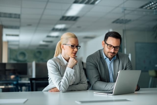Two professionals reviewing screening data on a laptop, representing automated background screening and SmartScreen solutions.