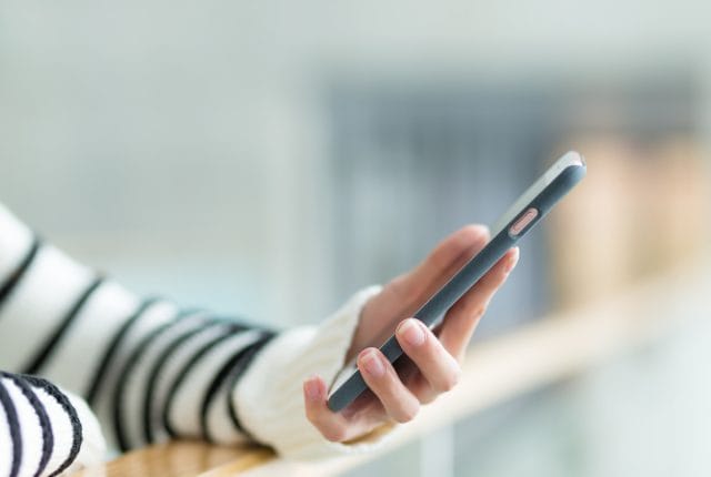 Person using a smartphone, representing social media screening during the hiring process.