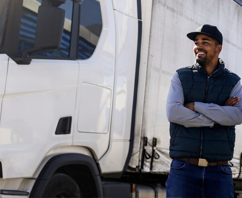 Man smiling beside a commercial truck, representing transportation workforce and logistics industry.
